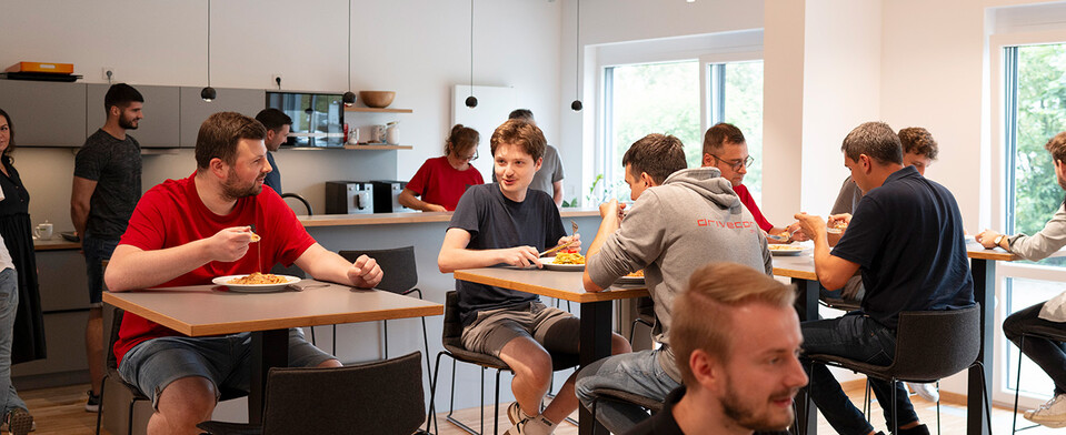 Mitarbeiter essen gemeinsam Lasagne